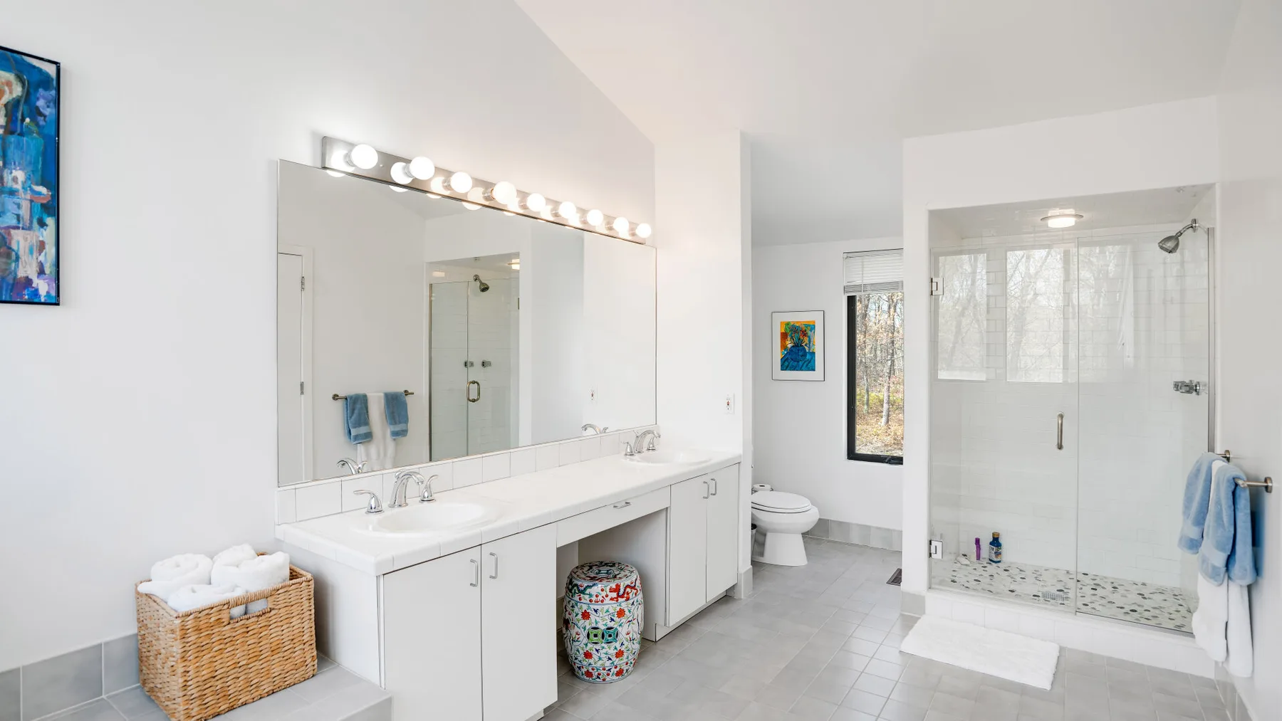 A bright bathroom with a long vanity and a glass-enclosed shower.