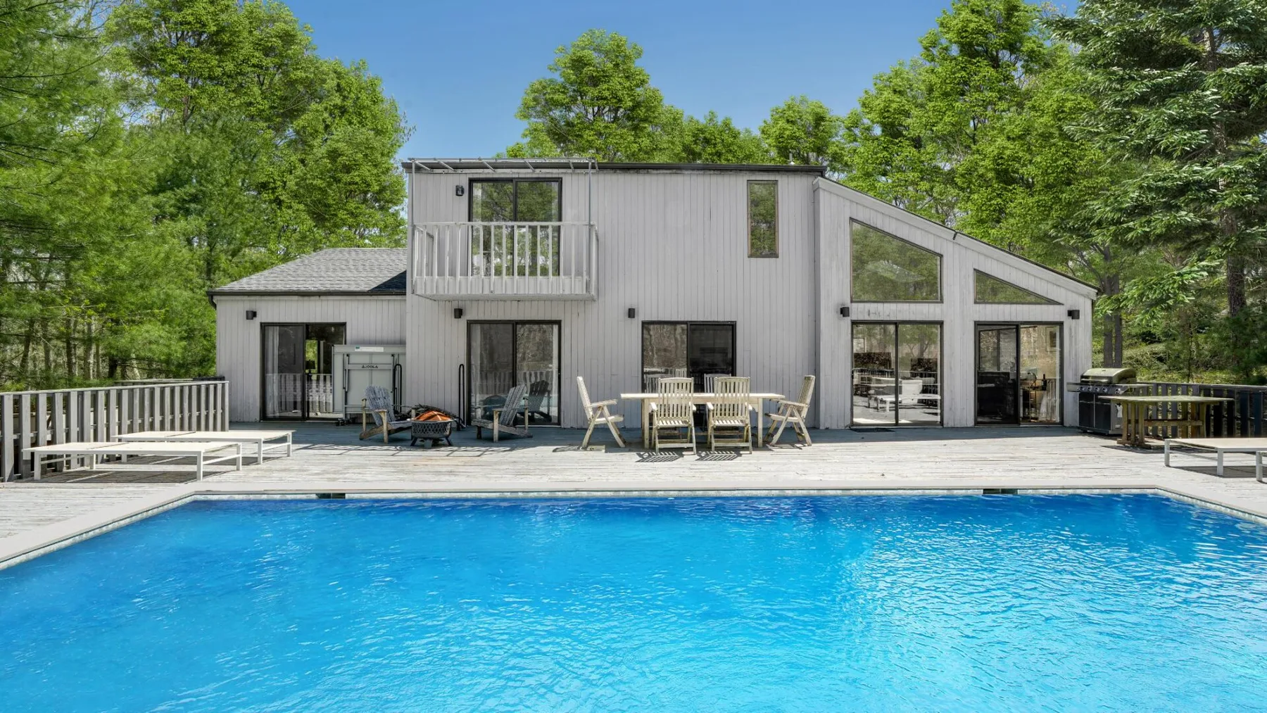 Una casa moderna da a una piscina y un patio con asientos al aire libre.