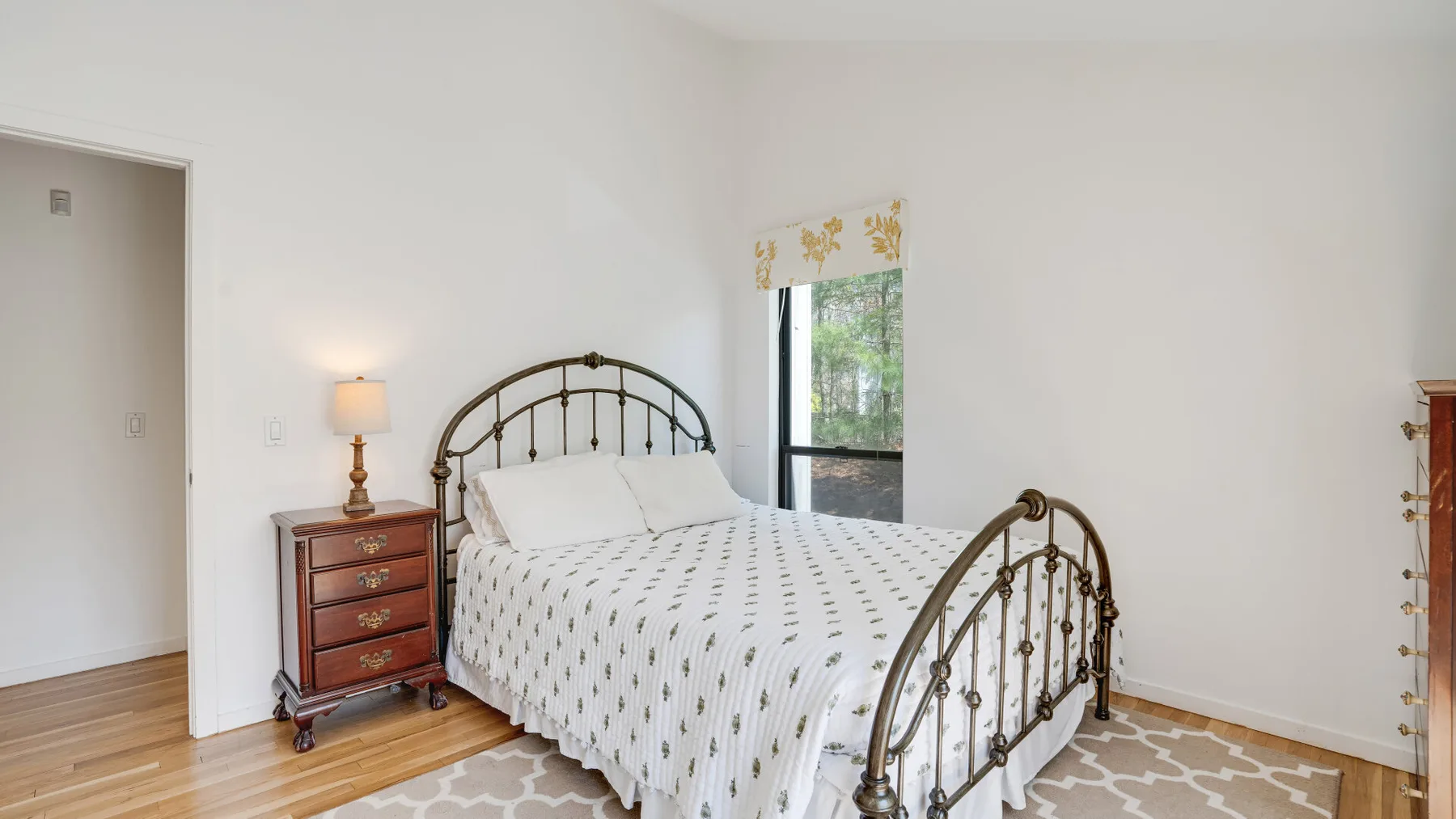 A bedroom with a metal bed, bedside table, and a window.