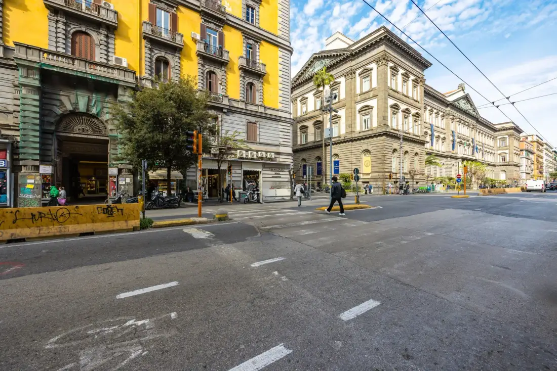 Una calle urbana con edificios históricos, peatones y cables aéreos.