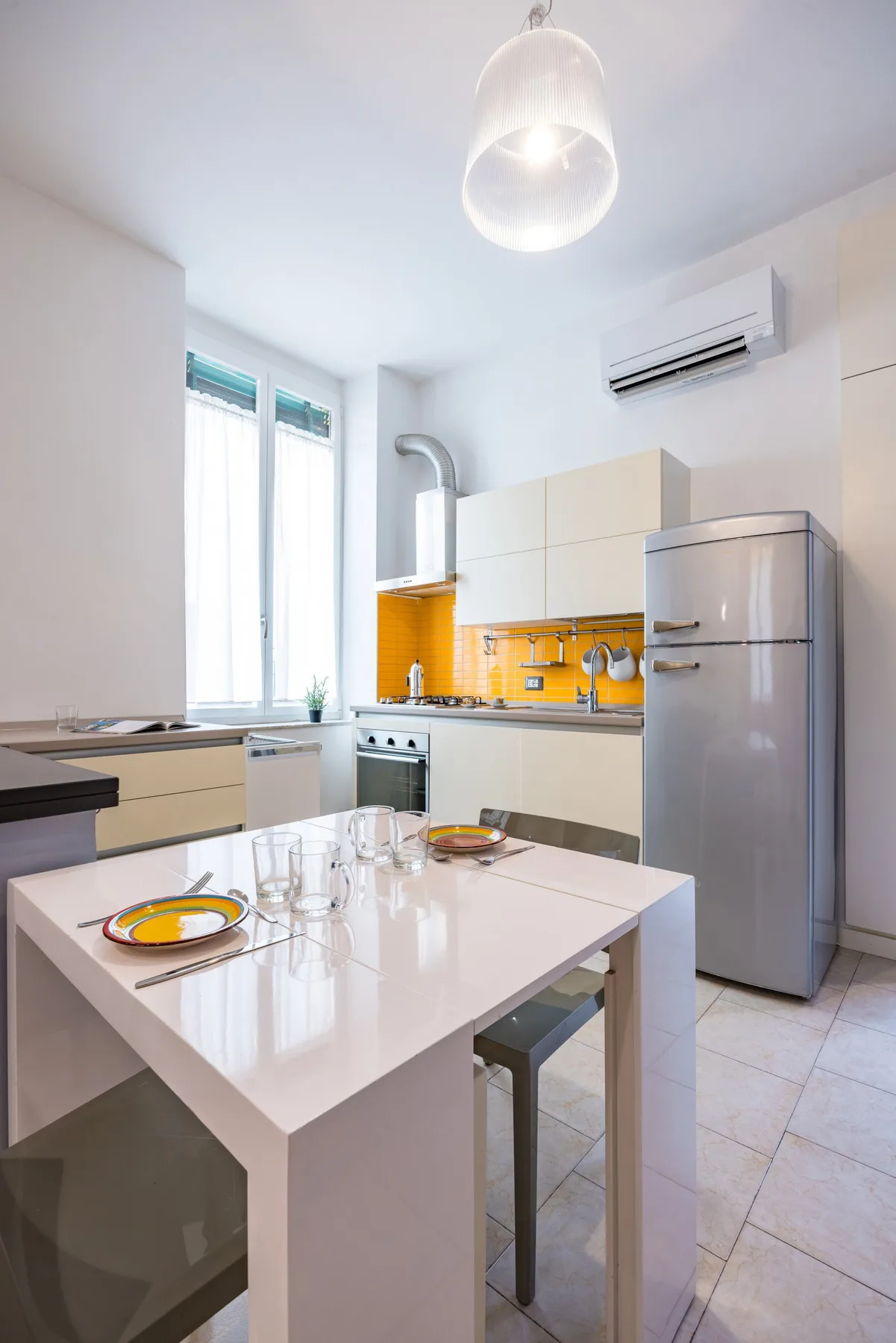 Una cocina luminosa con una mesa central y armarios de tonos claros.