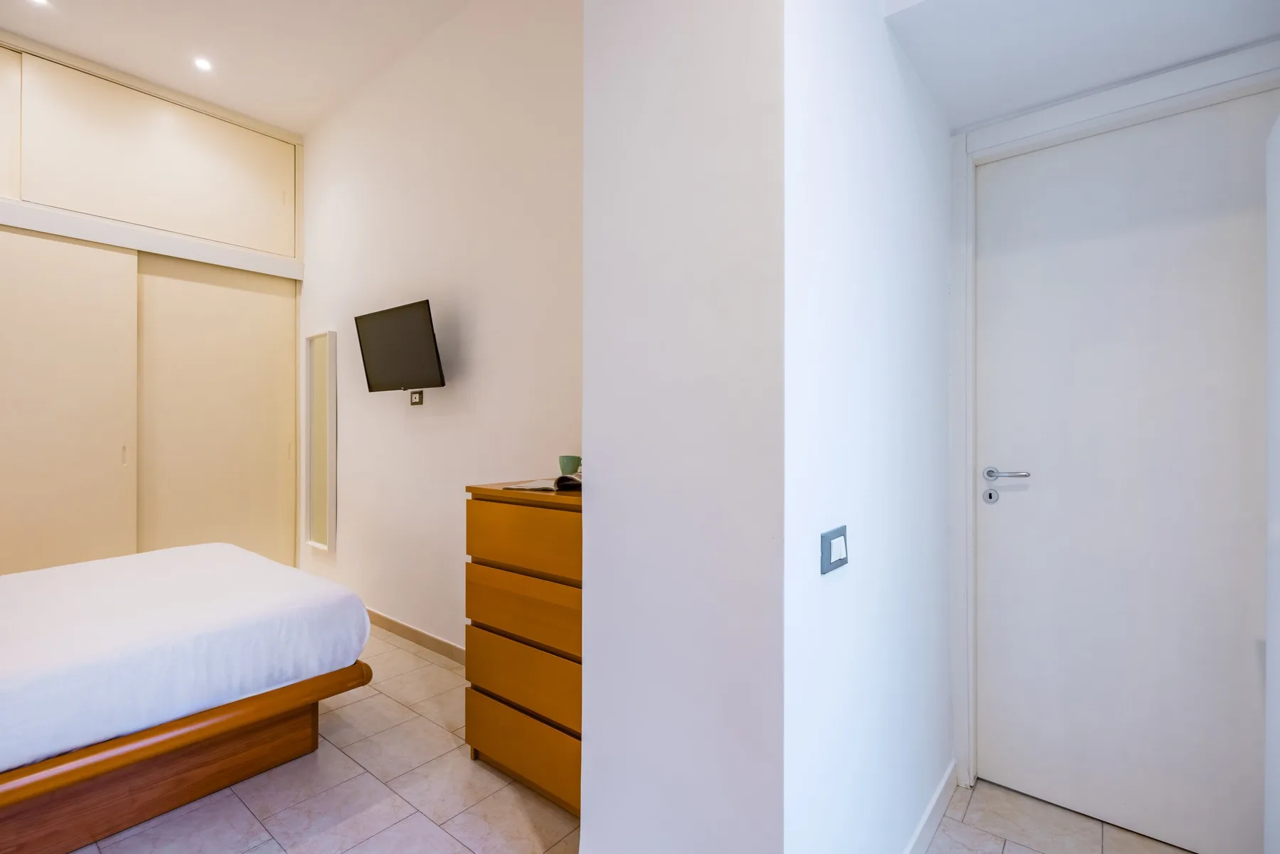 Un dormitorio con una cama y una cómoda de madera junto a un pasillo.