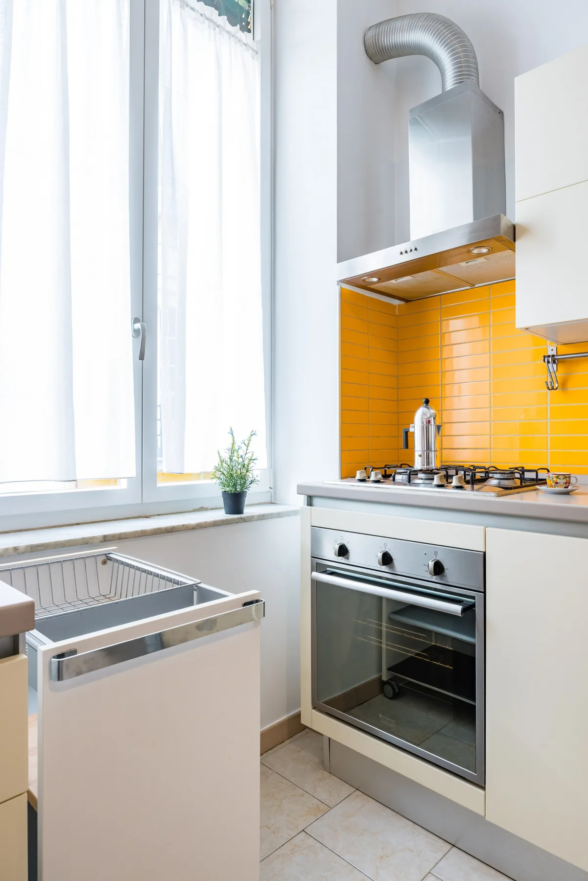 Una cocina luminosa con horno, estufa y salpicadero de azulejos naranjas.