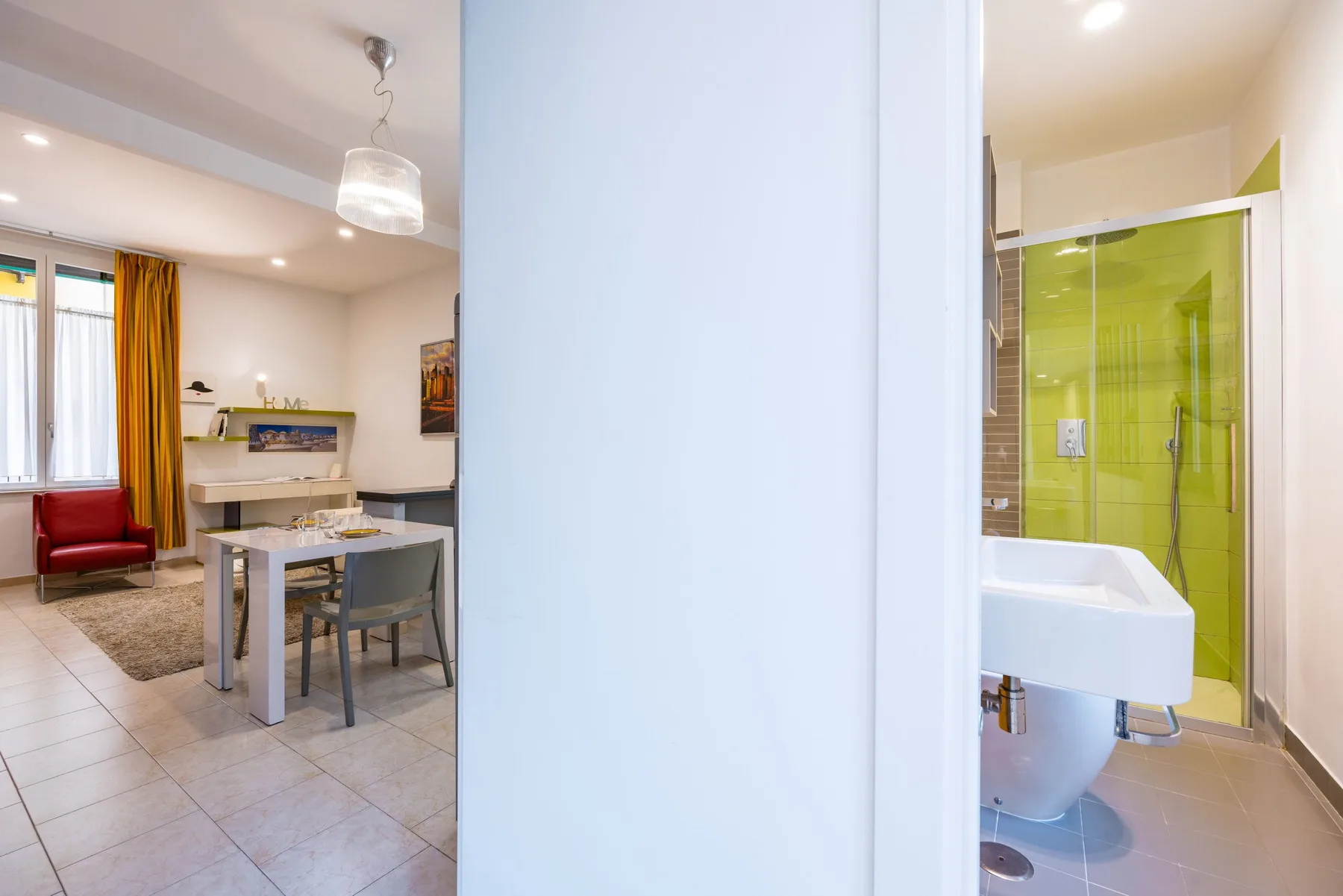 Un comedor de planta abierta junto a un baño con ducha de vidrio.