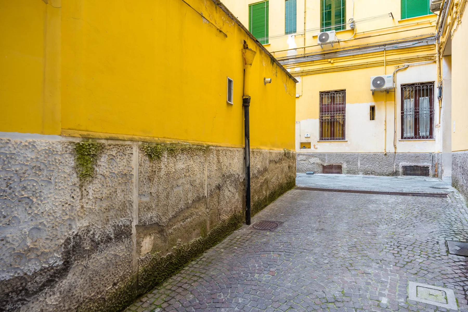Un patio empedrado rodeado de paredes de edificios amarillas y blancas.