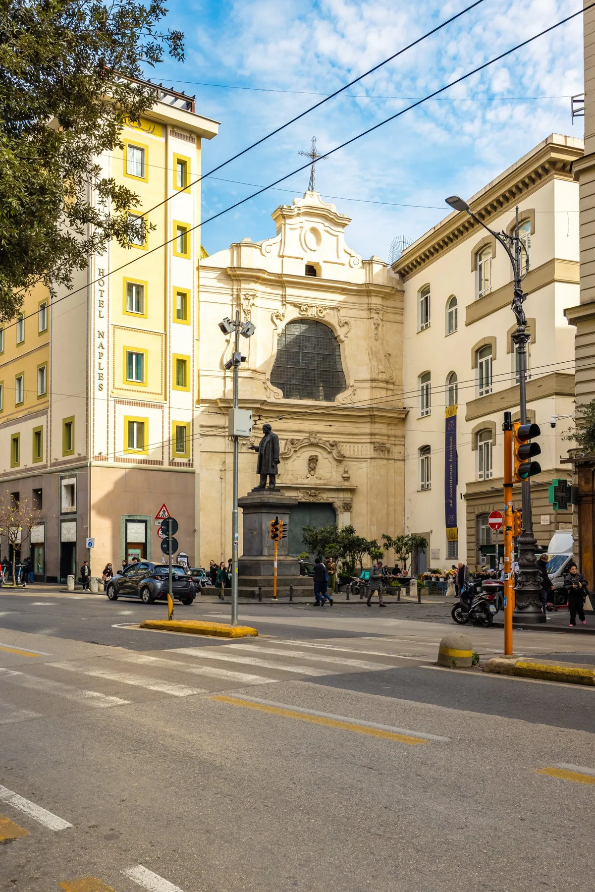 La fachada de una iglesia histórica se alza en un cruce urbano junto a edificios más altos.