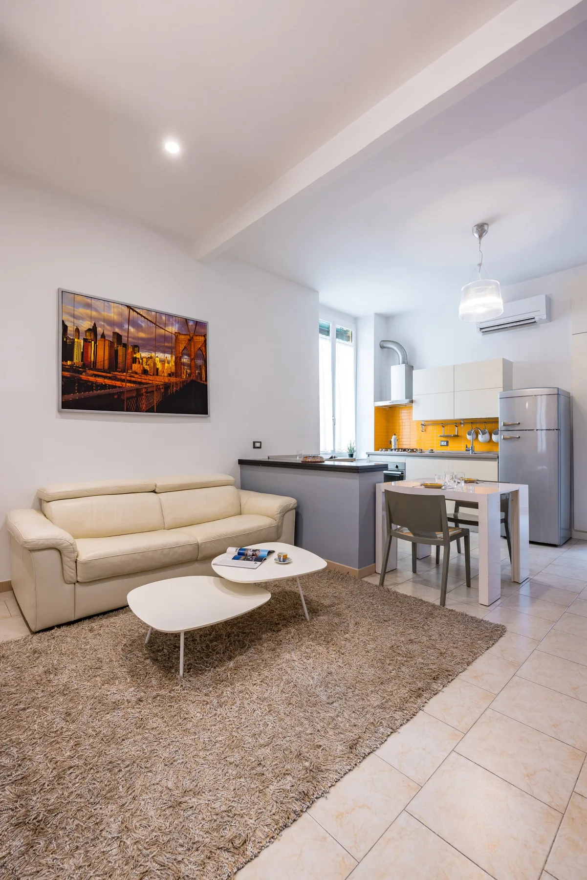 Una sala de estar con asientos junto a una cocina abierta y una mesa de comedor.