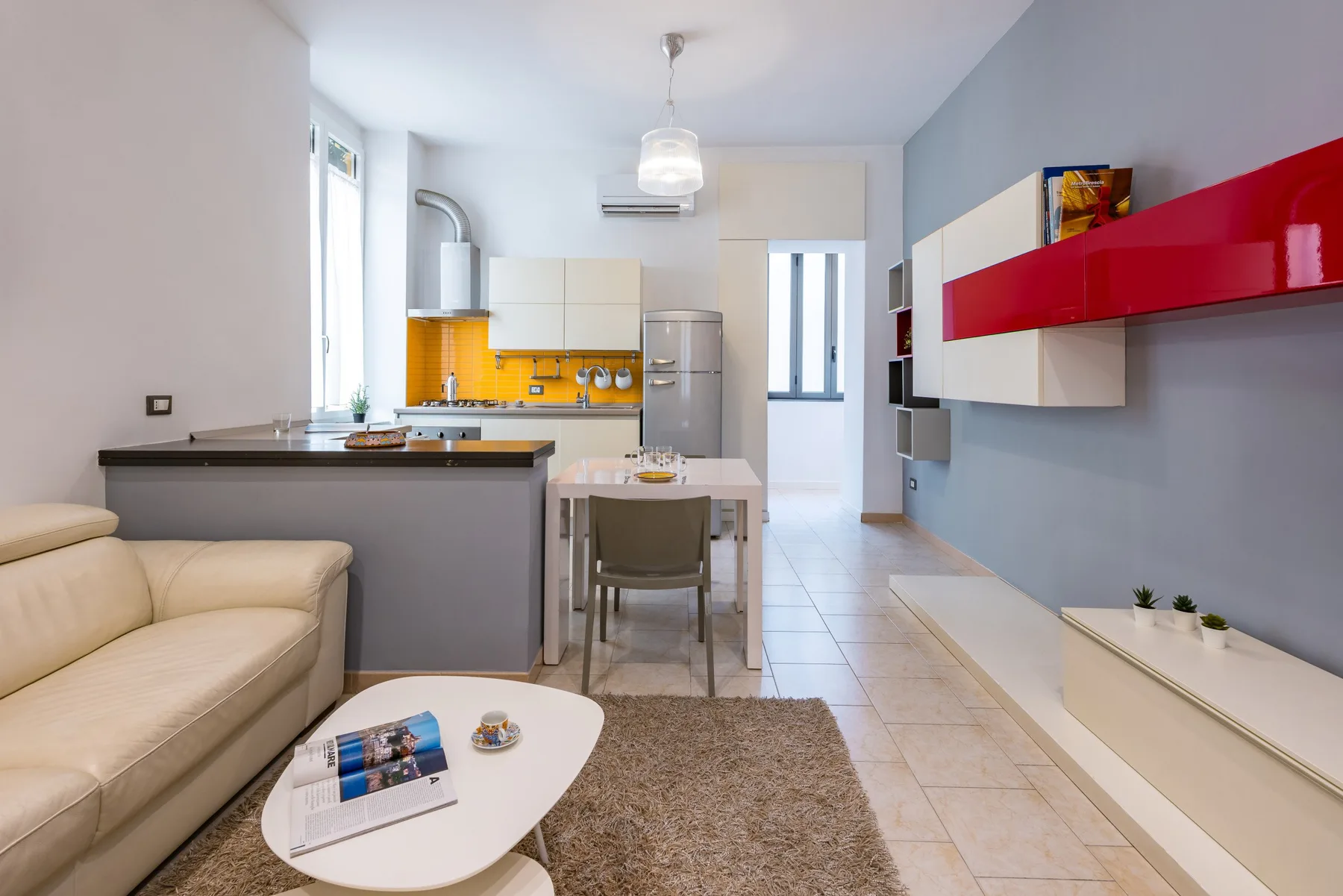 Una luminosa sala de estar con cocina abierta, mesa de comedor y asientos beige.