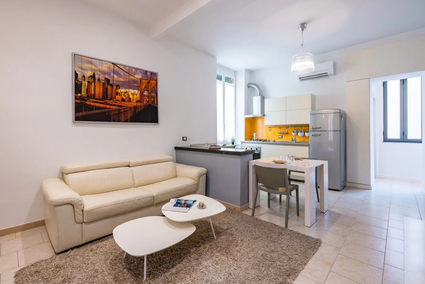 Sala de estar y cocina integradas con un sofá y una mesa de comedor.