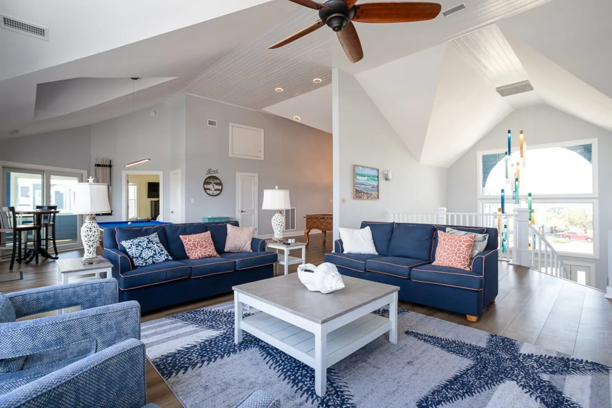 A bright living room with blue seating, a coffee table, and large windows.