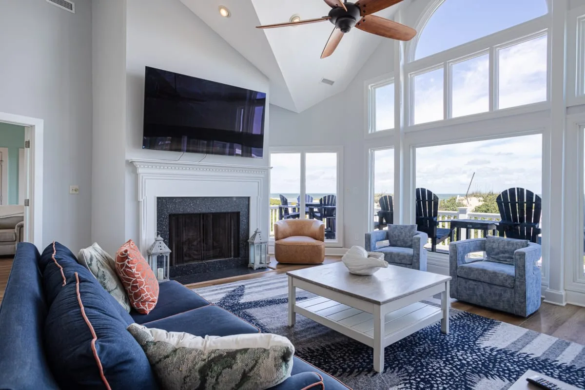 Una sala luminosa con grandes ventanas, una chimenea y asientos.