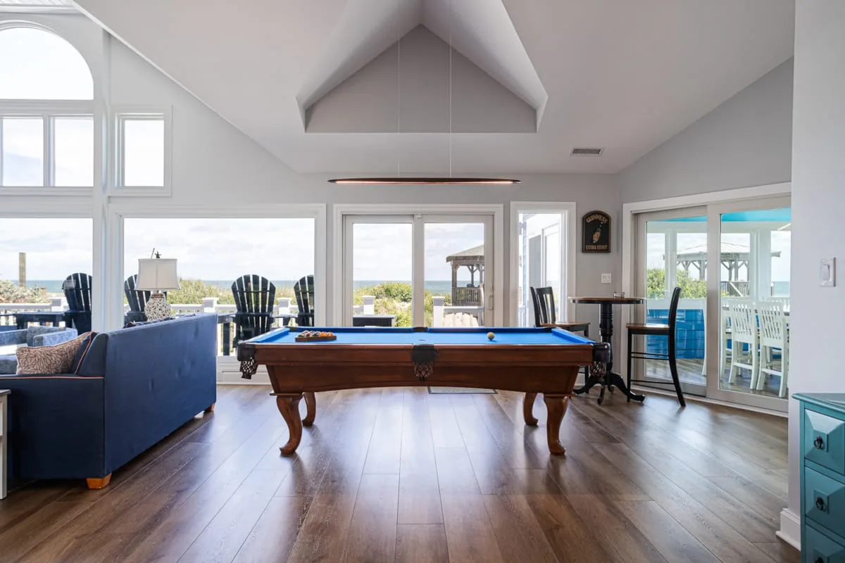 Una luminosa sala de juegos con una mesa de billar y grandes ventanas.