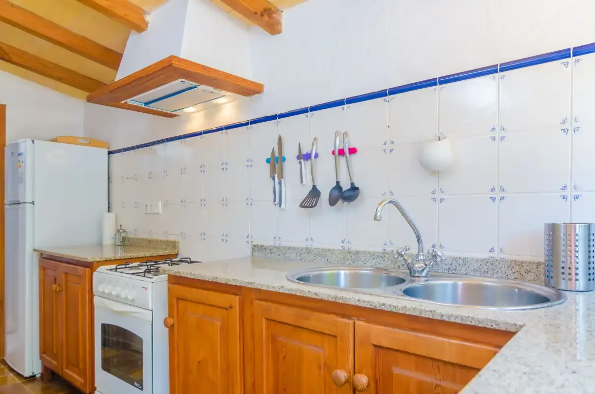 A kitchen with wooden cabinets, tiled walls, and a double sink.