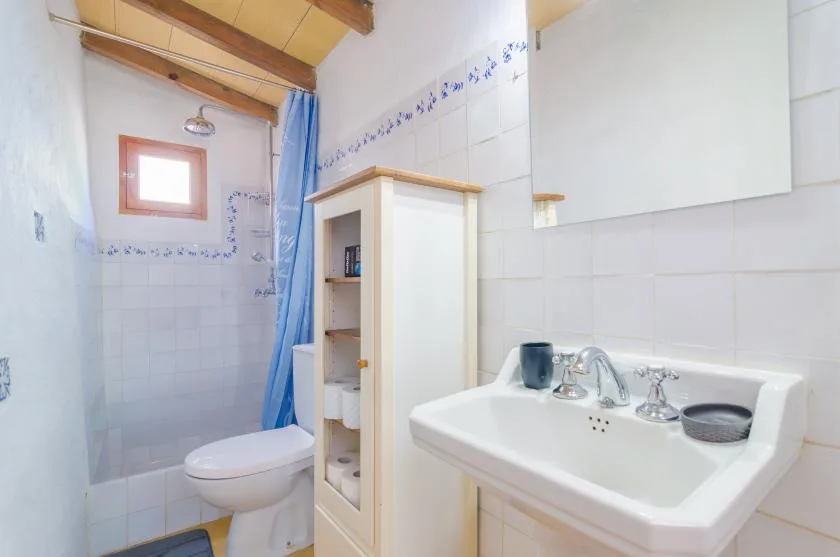 A tiled bathroom with a toilet, sink, and blue shower curtain.