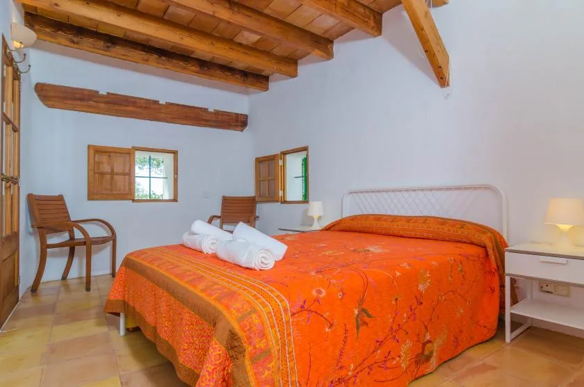 A bedroom with a double bed covered by a bright orange bedspread.