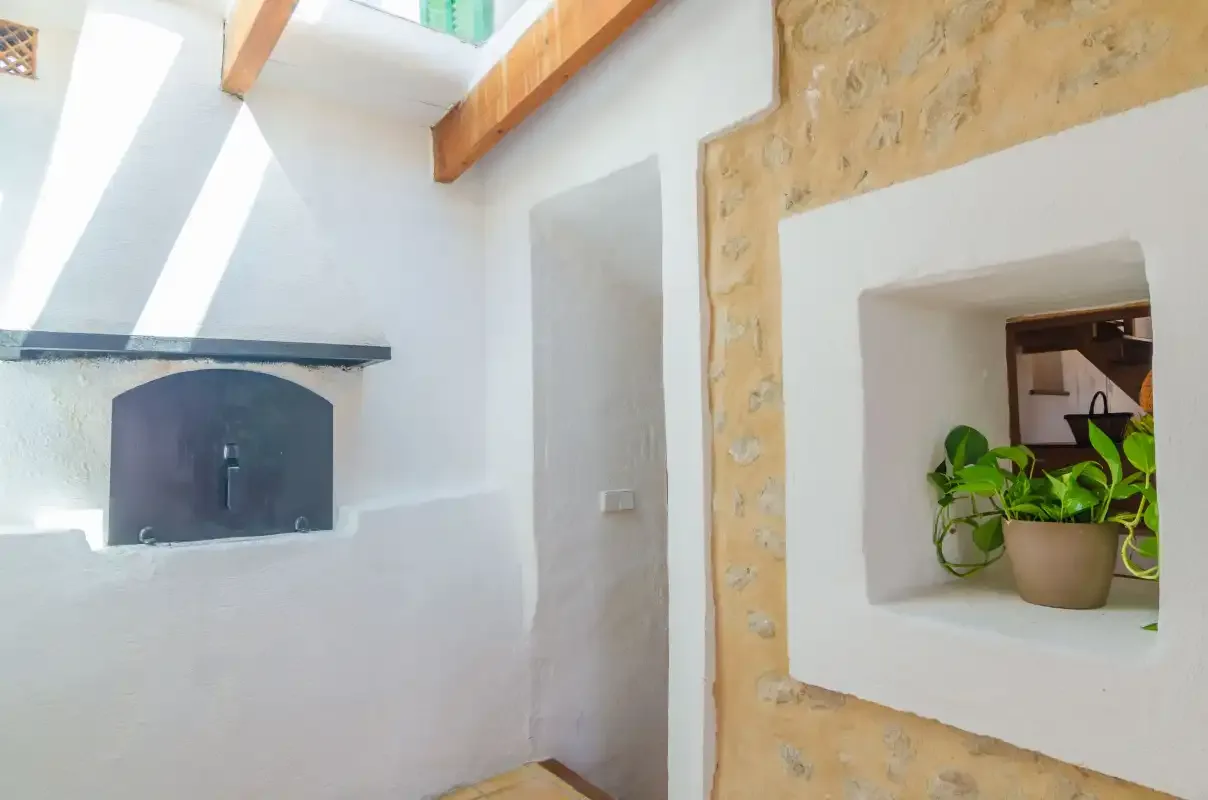 A bright interior with a built-in fireplace and a potted plant in a wall niche.