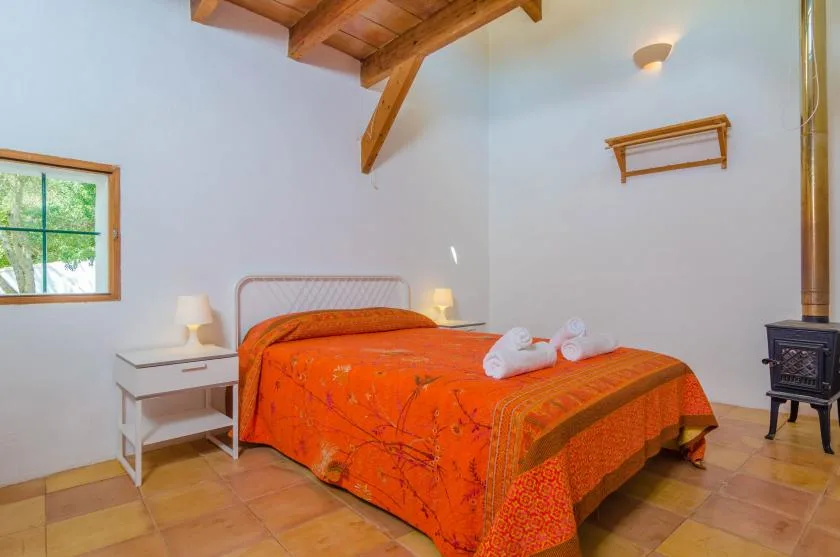 A bedroom with a double bed covered in a bright orange bedspread.
