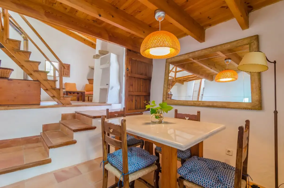A dining area with a wooden table beneath exposed ceiling beams.