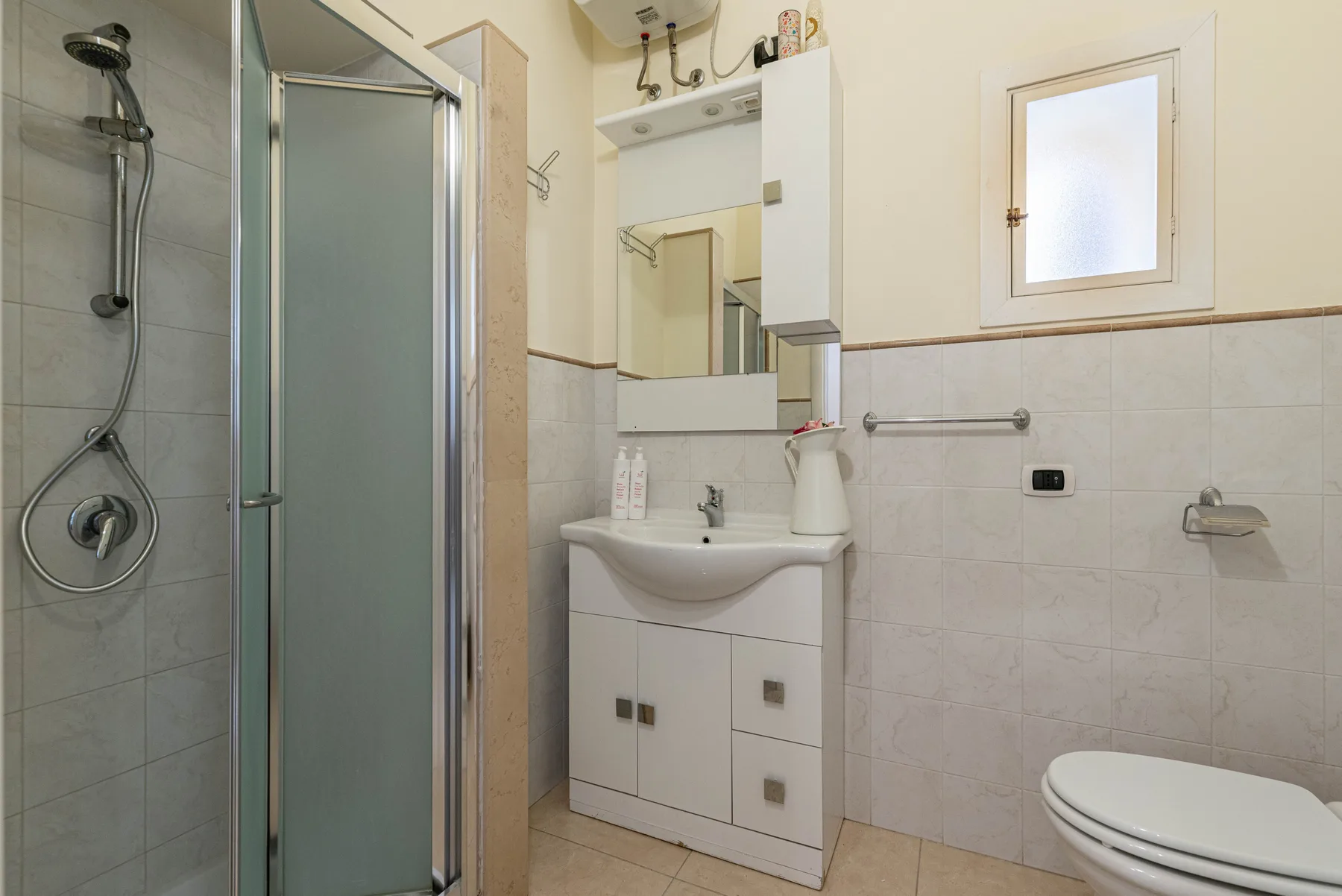 A bathroom with a shower, sink, and toilet.