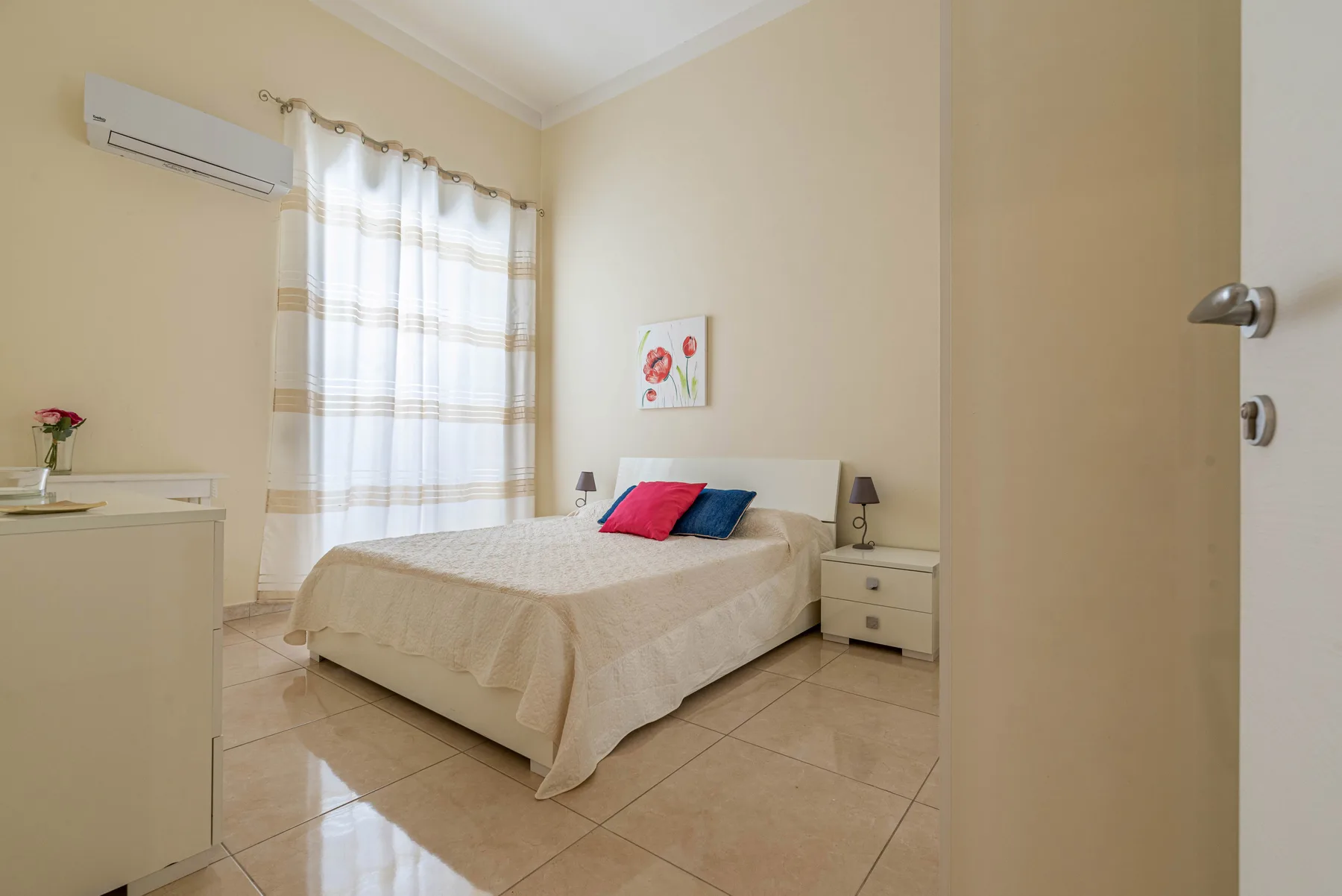 Un dormitorio con una cama, mesillas de noche y una ventana con cortinas.