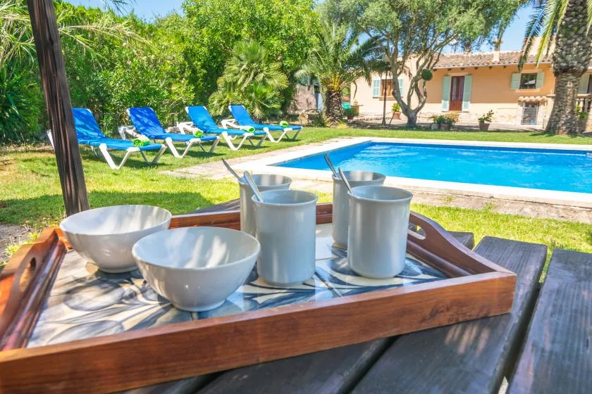 A poolside seating area with a serving tray and cups in the foreground.