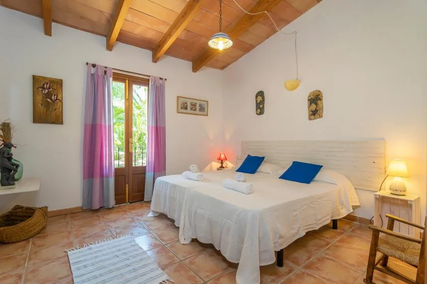 A bedroom with a large bed beneath a wooden-beam ceiling.