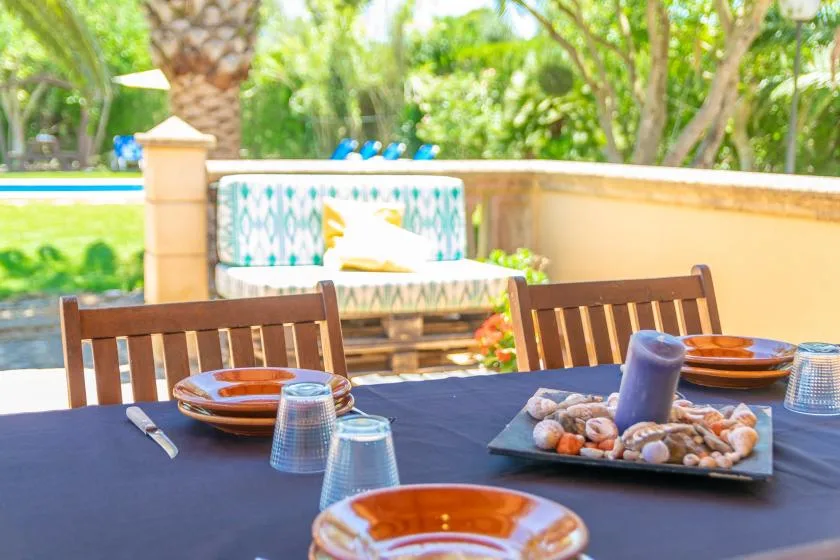 An outdoor dining table is set with plates beside a garden seating area.