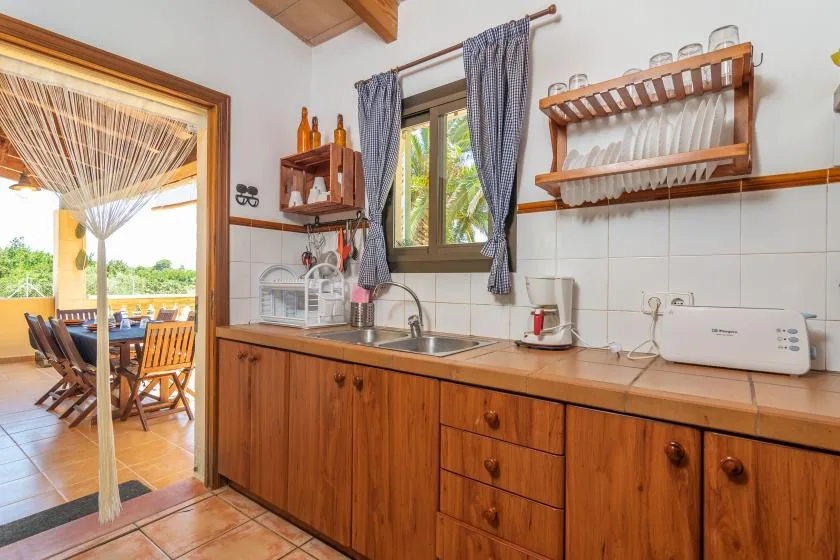 A kitchen with wooden cabinets, a sink, and a window overlooking an outdoor dining area.