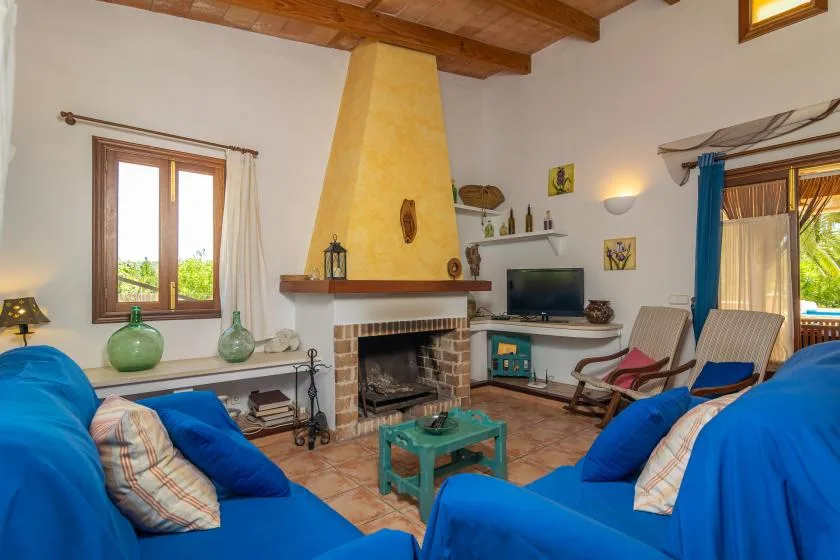 A living room with blue seating arranged around a fireplace and coffee table.