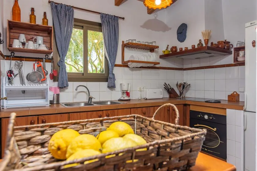 A kitchen with wooden cabinets, a window, and a basket of lemons.