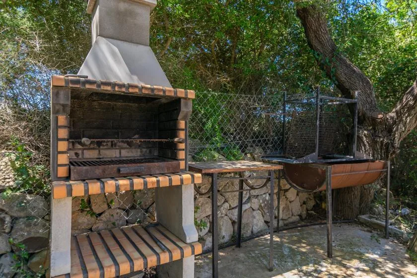 An outdoor cooking area with a brick barbecue beside a metal grill.