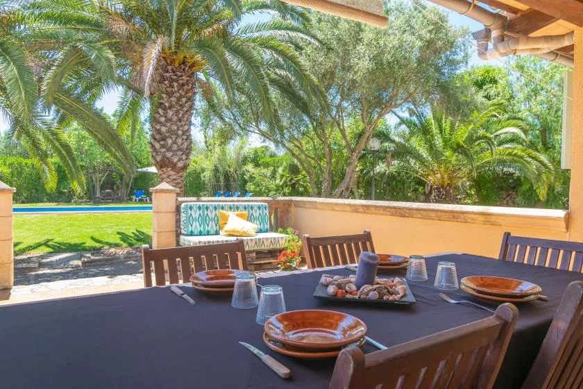 Outdoor dining area with a set table overlooking a lush garden.