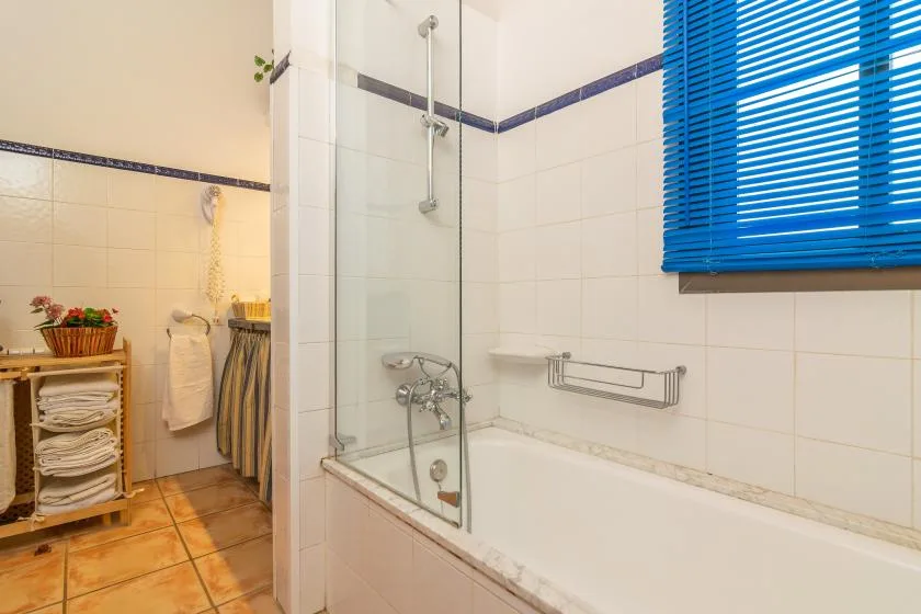 A tiled bathroom with a bathtub and glass shower screen.