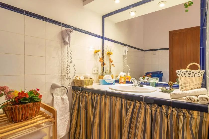 A bathroom vanity with a wide mirror, sink, and toiletries.