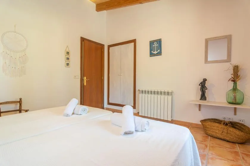 A bedroom with two neatly made beds and a radiator along the wall.