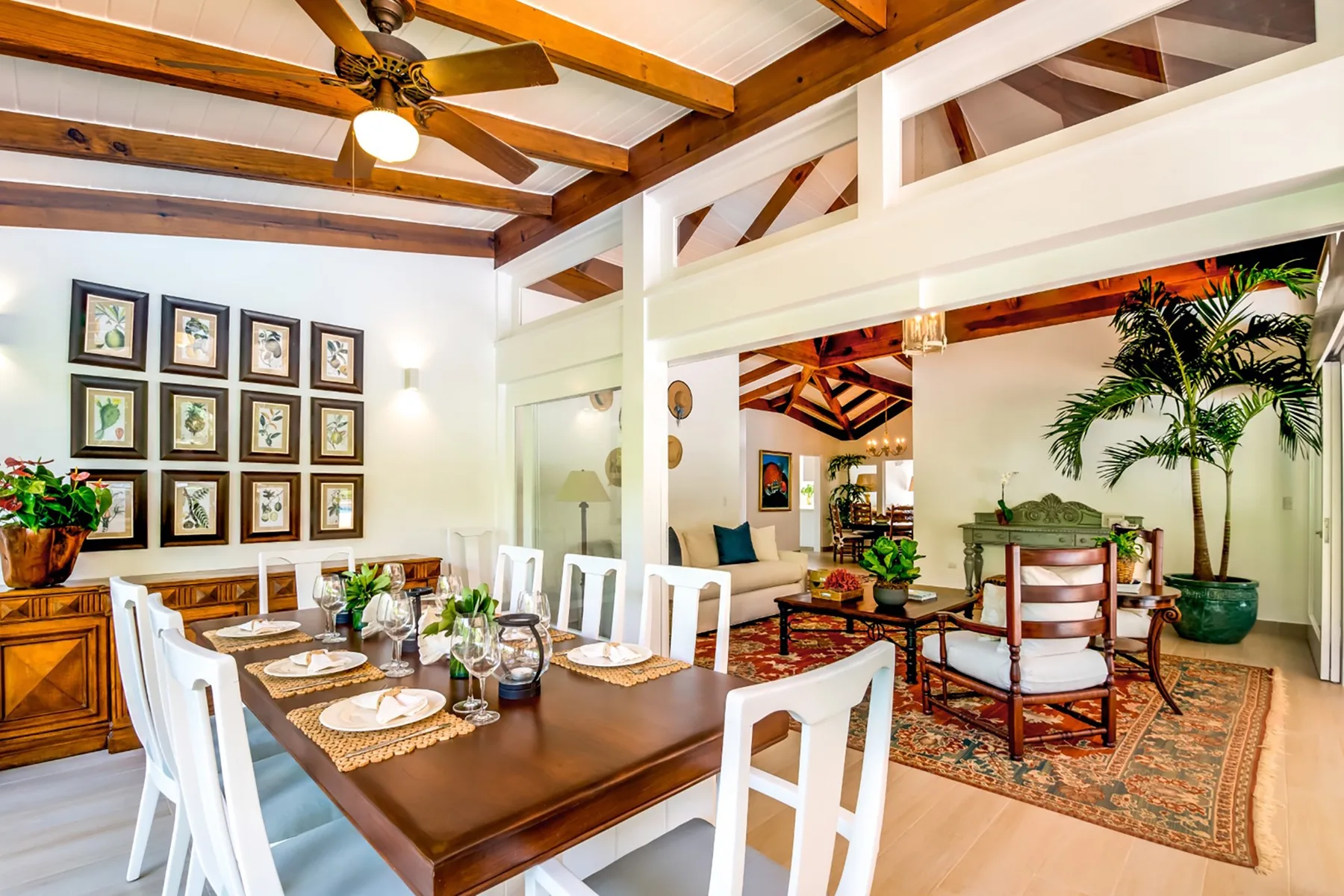 Un comedor se abre a una sala de estar, con una mesa de madera y plantas de interior.