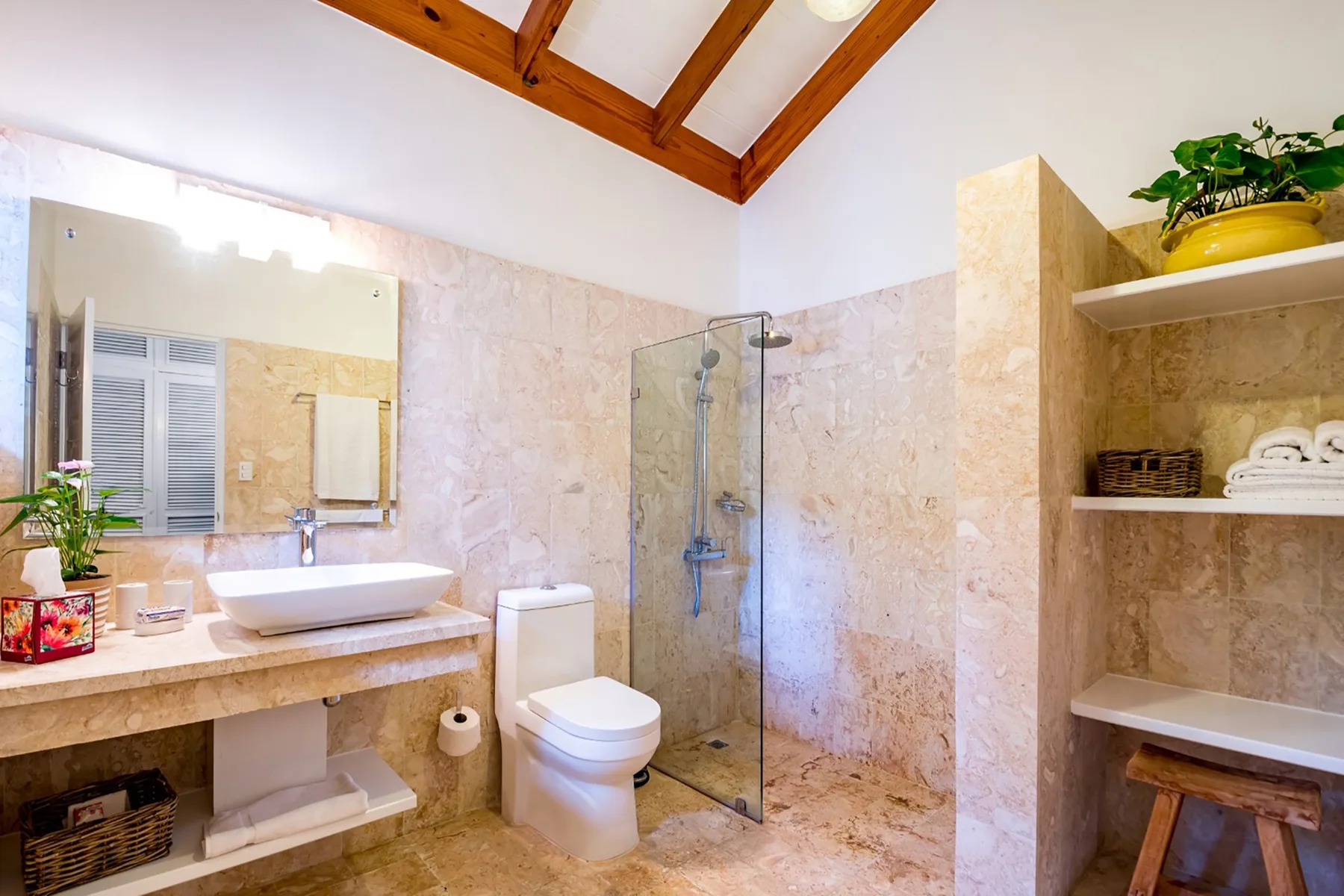 Un baño luminoso con lavabo, inodoro y ducha de vidrio.