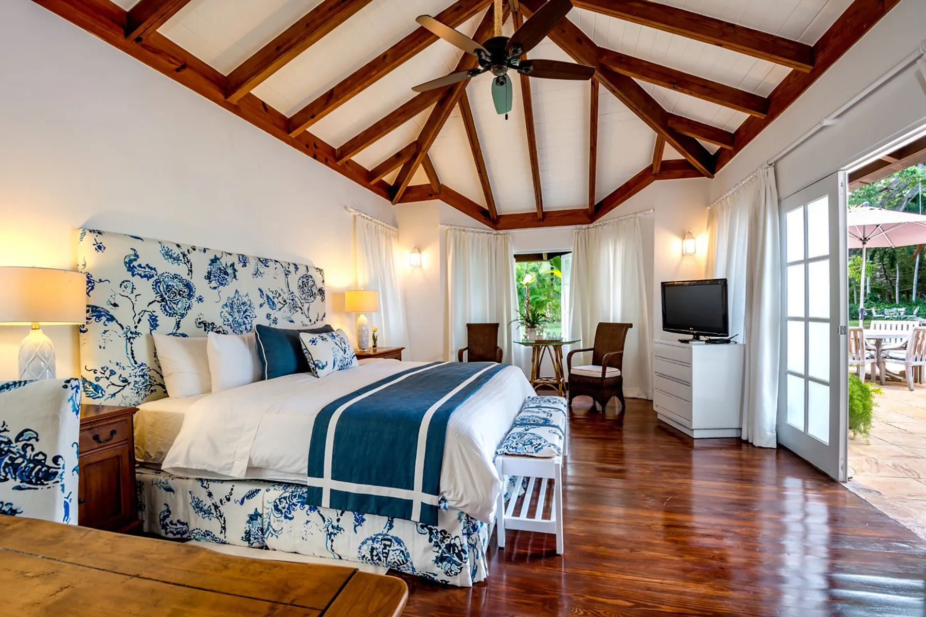 Un dormitorio luminoso con una cama grande bajo vigas de madera a la vista.