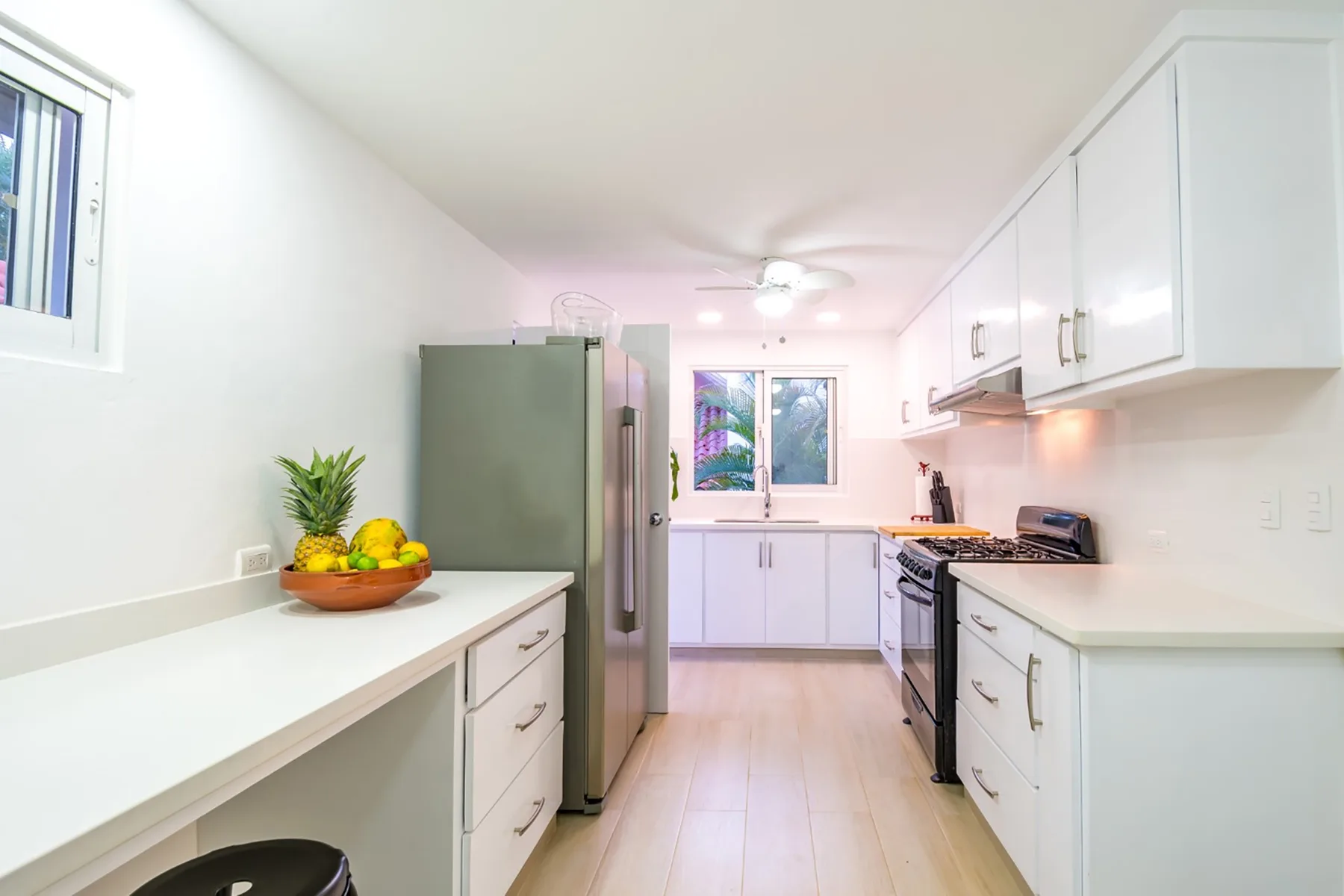 Una cocina luminosa con gabinetes blancos, encimeras y un refrigerador.