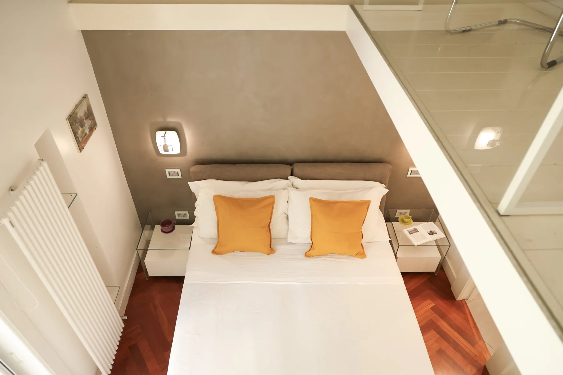 A bedroom with a neatly made bed and two orange pillows.