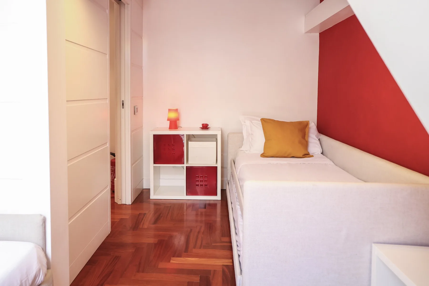 A compact bedroom with a single bed and a small bedside shelf.