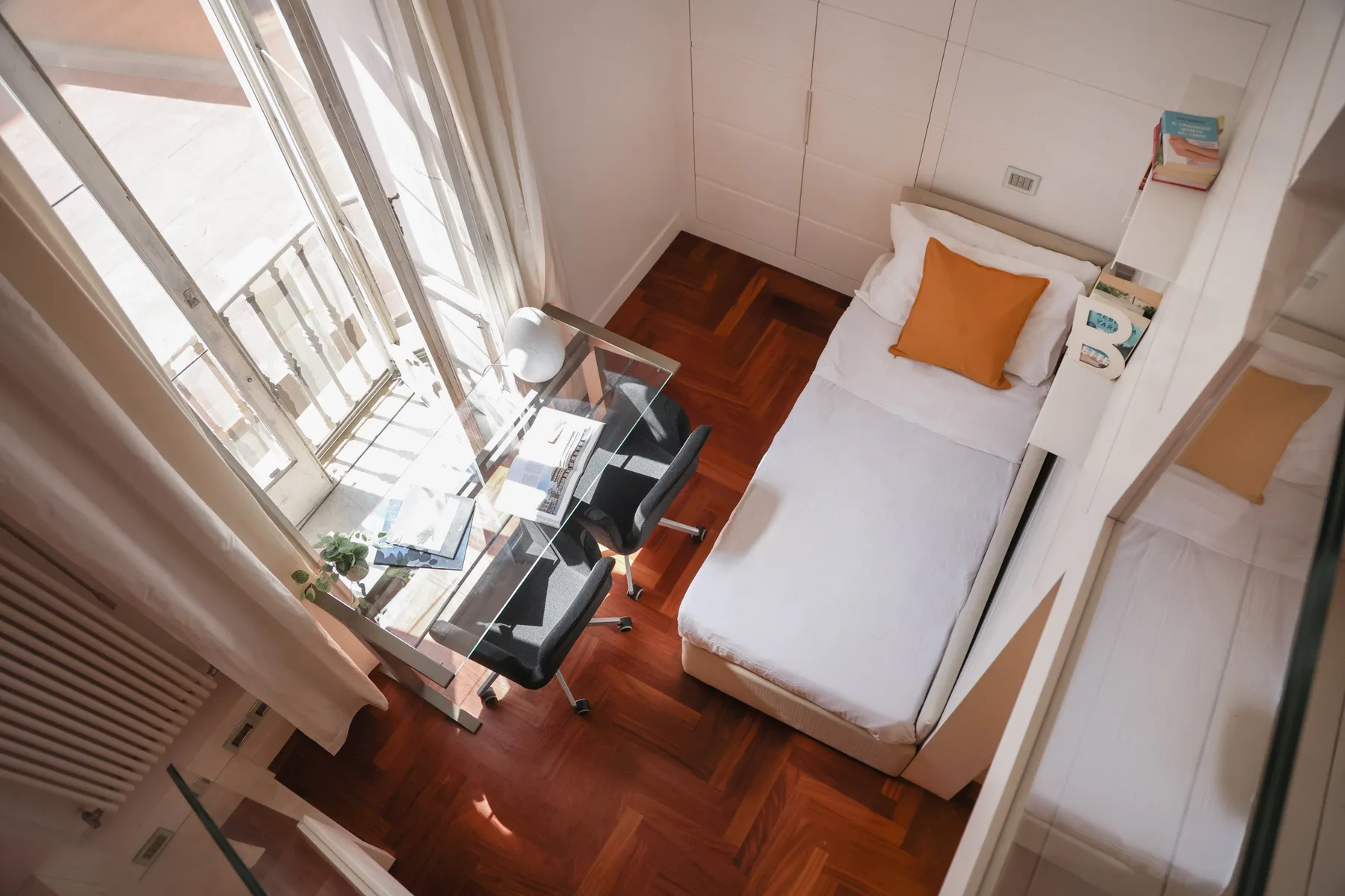 A compact bedroom with a single bed and a desk beside the window.