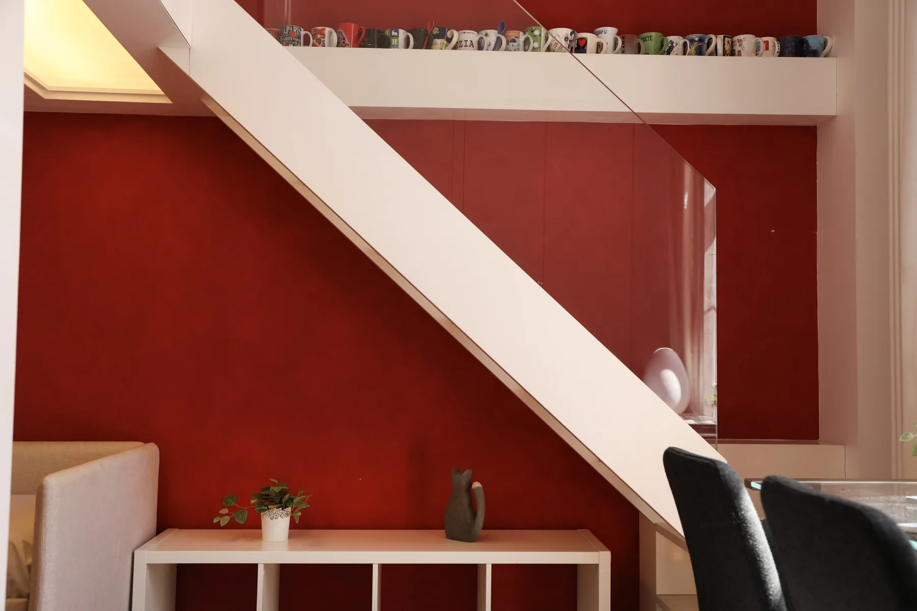 A dining area with a red wall, a long table, and dark seating.