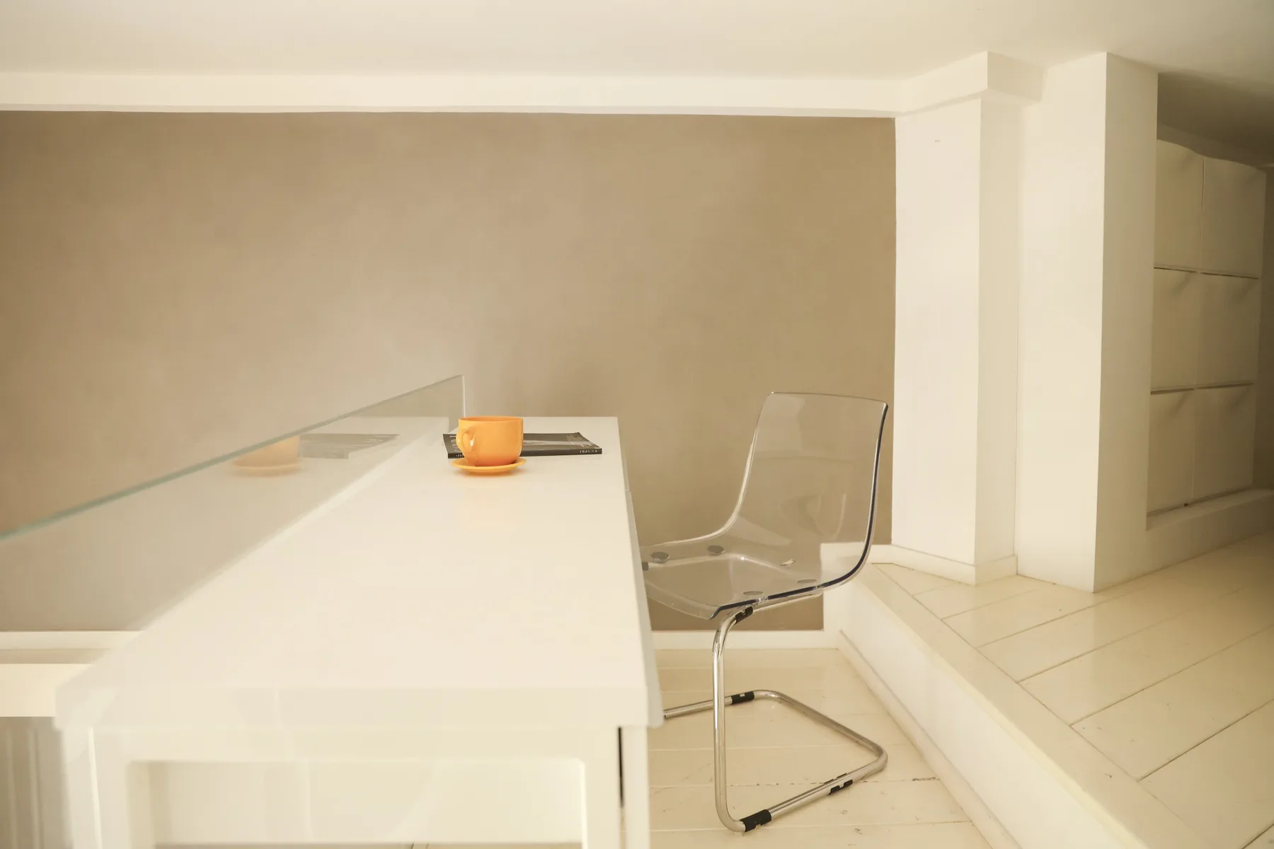 A bright dining area with a white table and transparent seating.