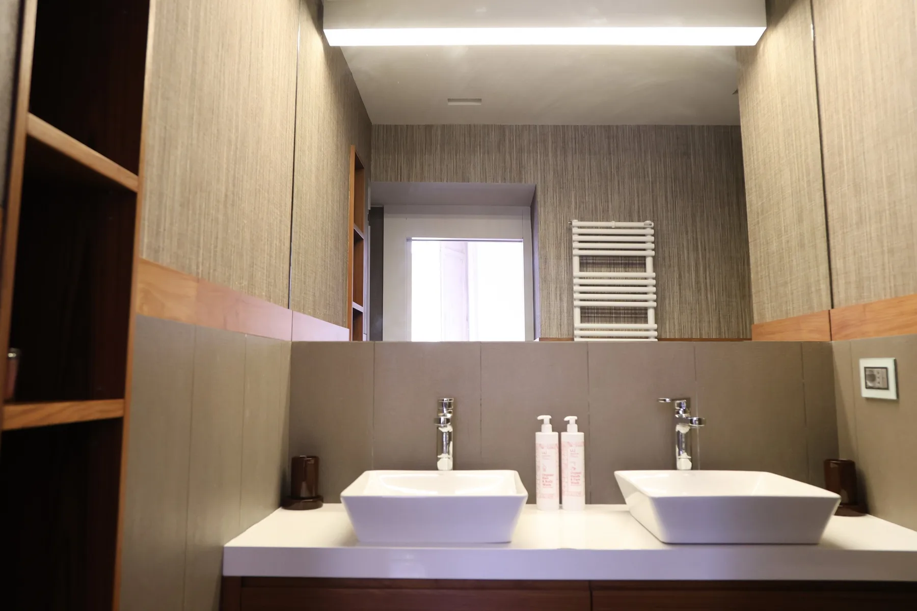 A bathroom vanity with two sinks and a towel rack.