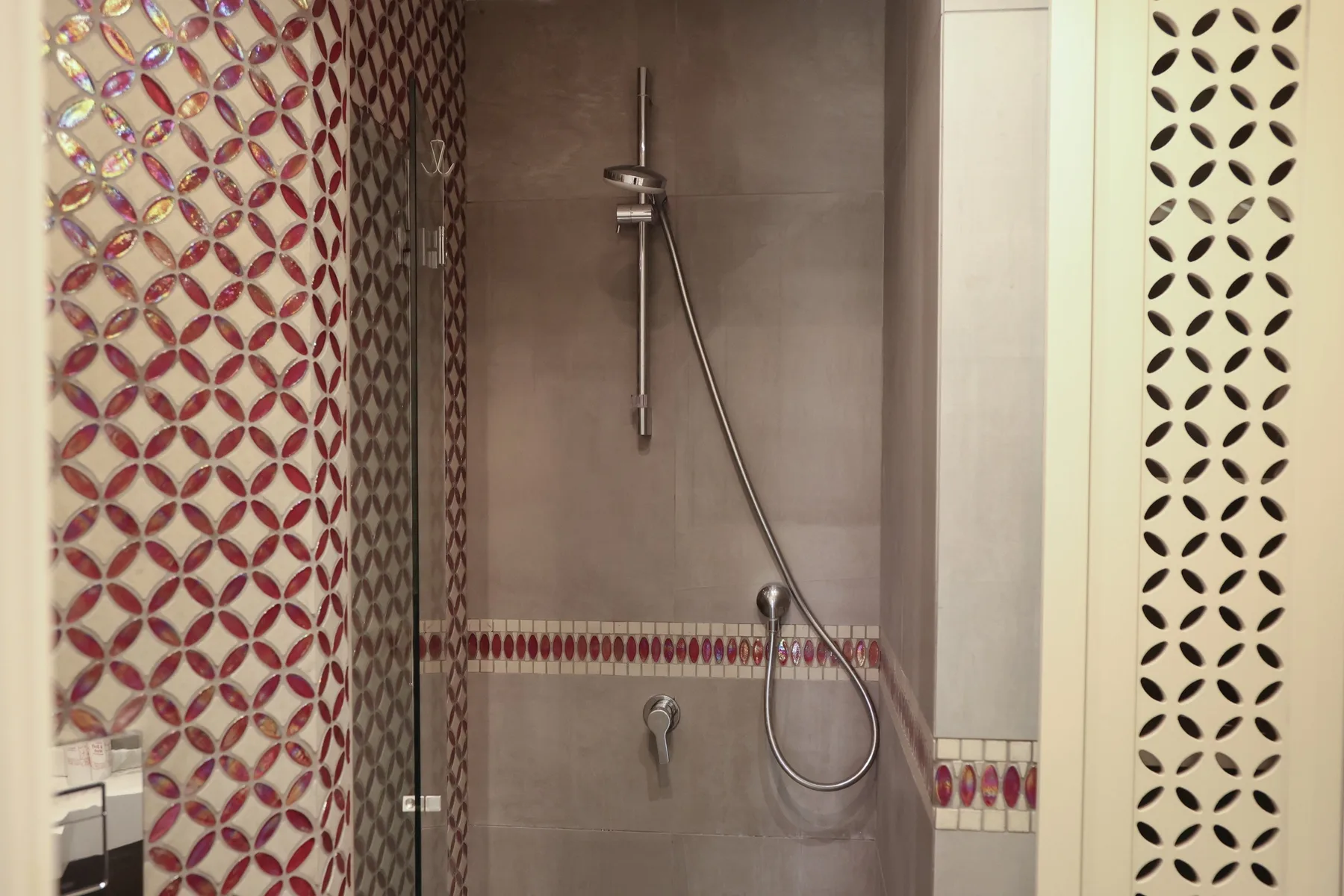 A tiled shower area with a wall-mounted showerhead and patterned tile accents.
