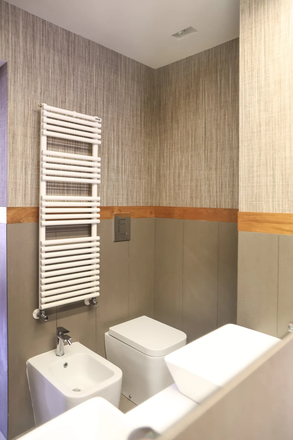 A bathroom with a wall-mounted towel warmer and white fixtures.