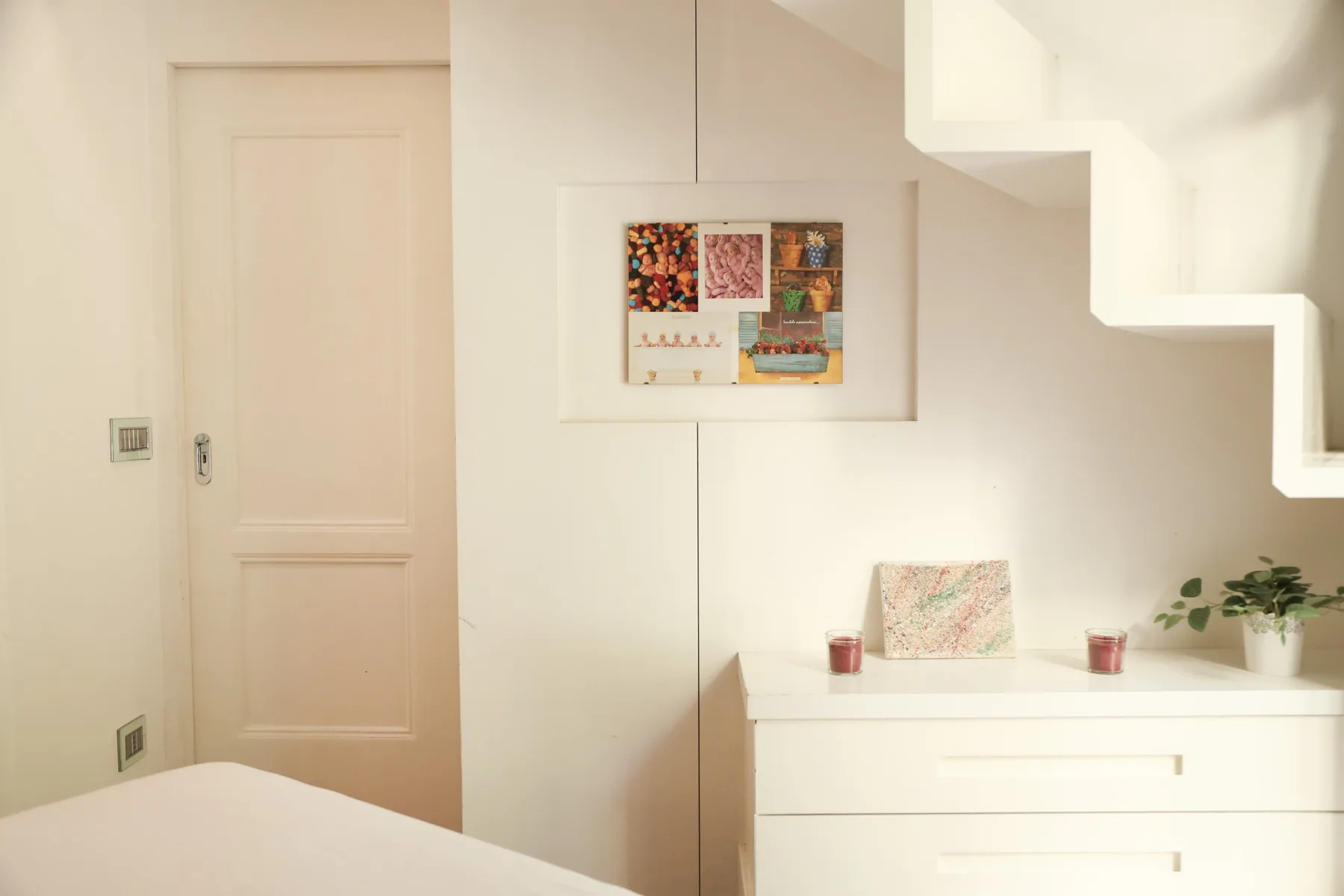 A bright bedroom with a bed, dresser, and framed artwork on the wall.