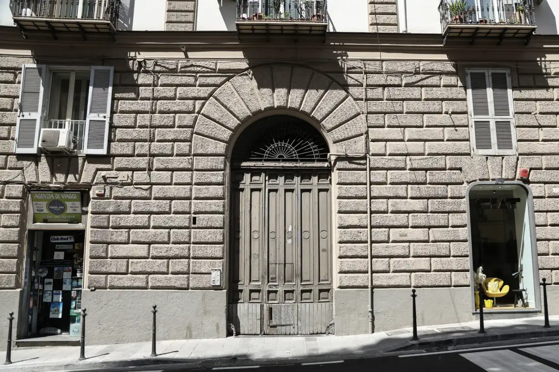 A stone building facade with a central arched entrance and windows.