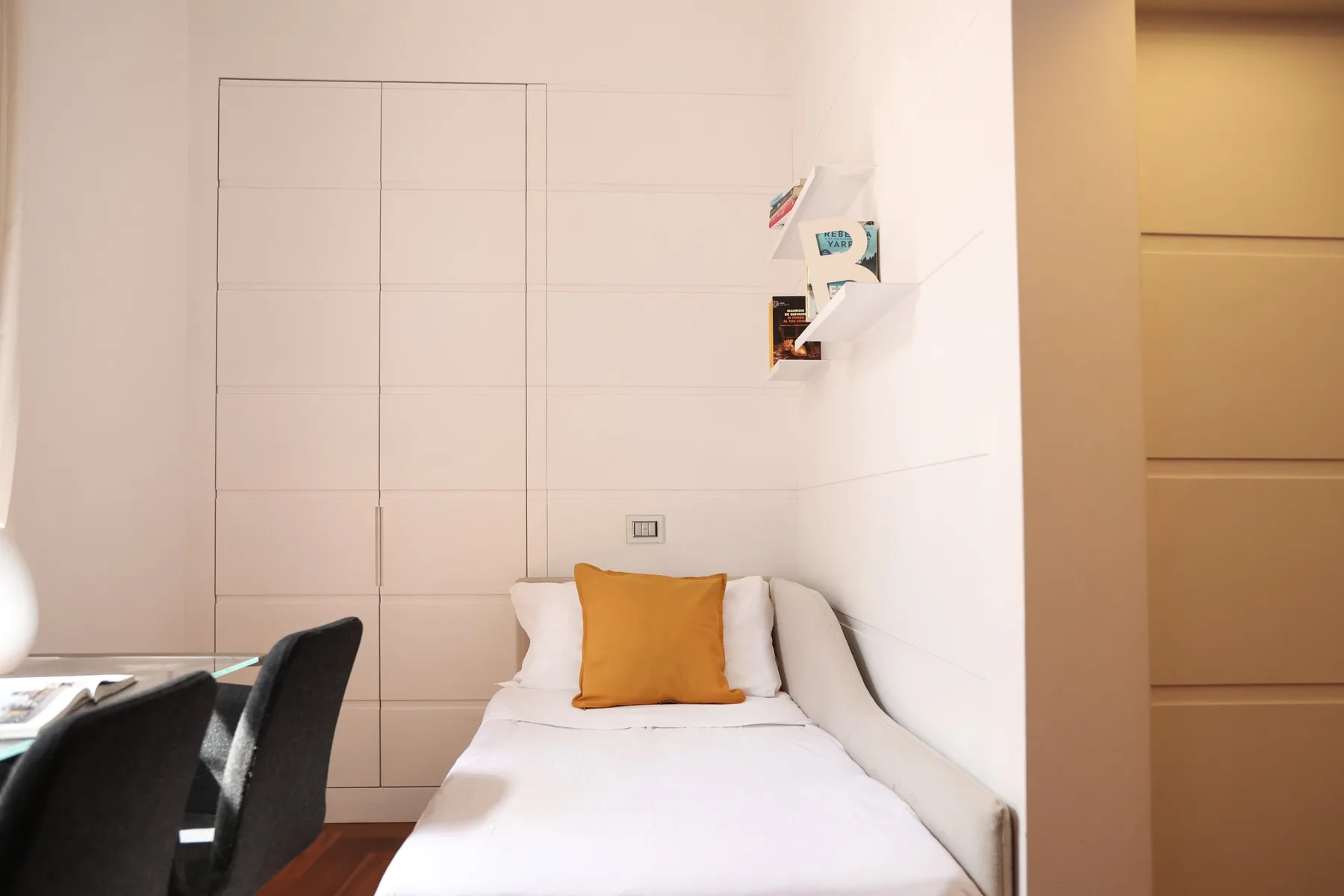 A bright bedroom with a single bed and a small desk area.